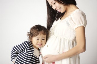 妊婦さんのお腹に耳を当てる子どもの画像│つわりの改善にも効果が期待できるビタミンB6とは？